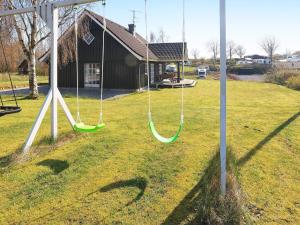 a swing set in a yard with a house at 8 person holiday home in L gstrup in Hjarbæk