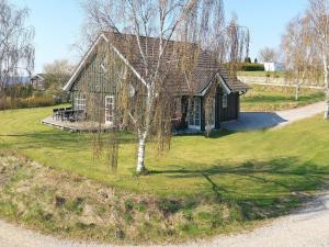 a small house on a lawn with a tree at 8 person holiday home in L gstrup in Hjarbæk