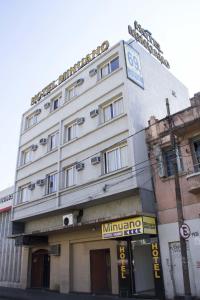 a white building with a clock on top of it at Minuano Hotel Home próximo ao aeroporto in Porto Alegre