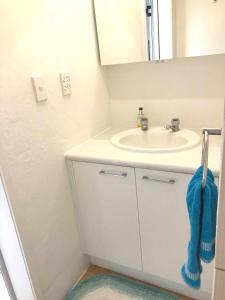 a white bathroom with a sink and a mirror at Avarua Escape, Rarotonga in Avarua