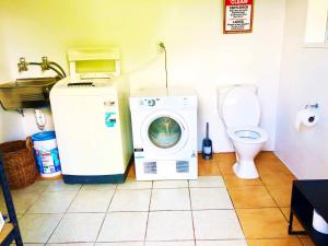 a bathroom with a washing machine and a toilet at Avarua Escape, Rarotonga in Avarua