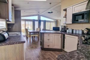 a kitchen with a counter top and a dining room at Stunning 6 Berth Lodge With Decking At Manor Park In Hunstanton Ref 23064k in Hunstanton
