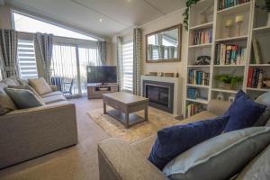 a living room with two couches and a fireplace at Stunning 6 Berth Lodge With Decking At Manor Park In Hunstanton Ref 23064k in Hunstanton