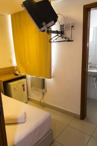 a room with a yellow curtain and a bed at Minuano Hotel Home próximo ao aeroporto in Porto Alegre +12 photos