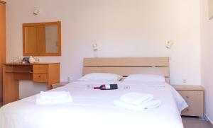 um quarto com uma cama branca e toalhas em Anchris Paleochora em Palaiochora