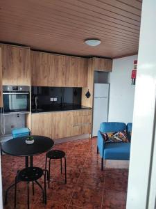 a living room with a table and a blue chair at Recanto do Oeste in São Pedro da Cadeira +5 photos