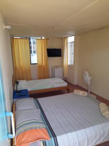 duas camas num pequeno quarto com duas janelas em Posada Henry Sede Centro em San Andrés