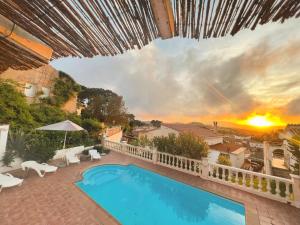 une villa avec une piscine et un coucher de soleil dans l'établissement Villa Mas Blau Munt, à Lloret de Mar