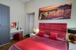 a bedroom with a red bed and a painting on the wall at VIVI A NAPOLI in Naples