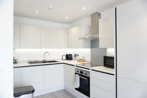 a white kitchen with white cabinets and appliances at The Madison Apartment by TTLG Stays in Hemel Hempstead