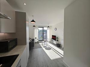 a kitchen and living room with white walls and wooden floors at The Madison Apartment by TTLG Stays in Hemel Hempstead