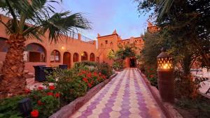 a walkway in front of a building with flowers at Kasbah Ait BenHadda in Skoura