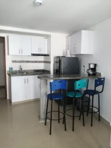 a kitchen with white cabinets and blue bar stools at Ocean blue Ed Conquistador in Cartagena de Indias