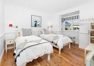 two beds in a white room with wooden floors at Hamptons Escape in Gerroa