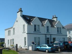 a blue car parked in front of a white house at The Studio in Lochmaddy