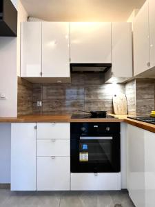 a kitchen with white cabinets and a black oven at Downtown Apartment in Krakow