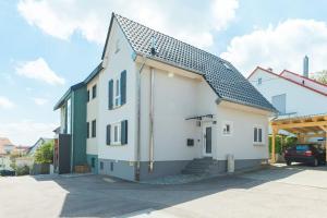 een wit huis met een zwart dak bij Lemon Suites: Traumhaus in Filderstadt in Filderstadt