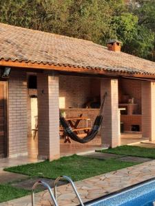 a pavilion with a hammock and a pool at Chácara Recanto Feliz in Ibiúna