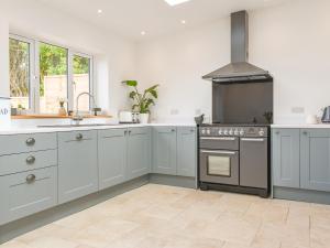 a kitchen with white cabinets and a stove top oven at Rose Cottage in Abbotsham