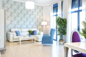 sala de estar con sofá blanco y sillas azules en Apartamento Guadiana RÍA - Centro, en Ayamonte