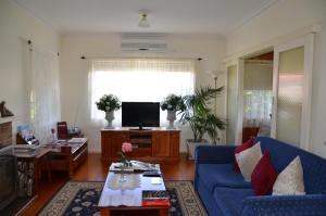 a living room with a blue couch and a tv at Admurraya House Bed & Breakfast in Rutherglen