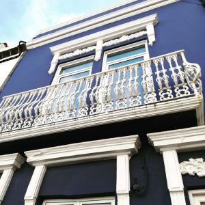 een blauw gebouw met een wit balkon bij A-Típica GuestHouse in Ponta Delgada