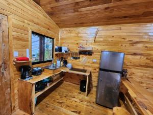 a kitchen in a wooden cabin with a refrigerator at Cabaña el Faisán, Jardín de Dota in Jardín