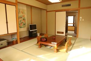 sala de estar con mesa, sillas y TV en Akasawa Onsen Ryokan, en Nasushiobara