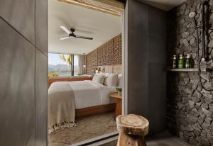 a bedroom with a bed and a stone wall at 1 Hotel Hanalei Bay in Princeville