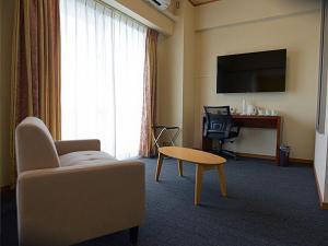 a living room with a couch and a table and a tv at Jisco Hotel Obama Onsen in Obama