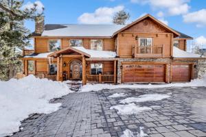 ein Blockhaus im Schnee mit Einfahrt in der Unterkunft Cozy Lakeview Hideaway by Big Bear Vacations Amazing Fawnskin Log Cabin Chalet in Fawnskin