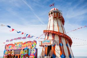 a lighthouse with flags on it next to two buildings at Spacious 8 Berth Caravan At Heacham Beach Holiday Park In Norfolk Ref 21027b in Heacham