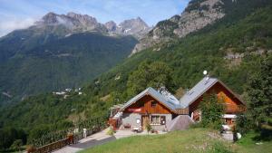 una casa su una collina con montagne sullo sfondo di Chez Passoud a Vaujany