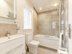a bathroom with a toilet and a tub and a sink at Rosemary Lodge in Willington