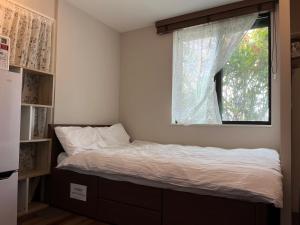 Cama en habitación con ventana en バラ苑目黒 目黒駅徒歩7分　恵比寿徒歩13分　静かな高級住宅　設備充実　花見名所, en Tokio