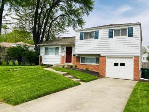 a white house with a red door and a grass yard at The Cranbrook- Close to OSU-Downtown Columbus-Short North-Clintonville-Upper Arlington in Columbus