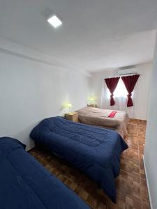 a bedroom with two beds with blue comforters at Apart Hotel Chilecito in Chilecito