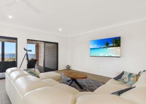 ein Wohnzimmer mit einem weißen Sofa und einem Tisch in der Unterkunft ESCAPE WITH A VIEW in Emu Park