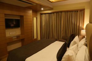 a hotel room with a bed and a television at The Fern Residency Mundra in Mundra