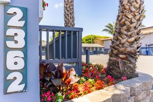 a sign for a hotel with flowers next to a palm tree at The Monterey Fireplace Inn in Monterey