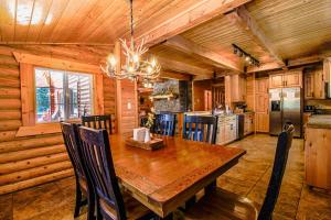 a dining room with a wooden table and a kitchen at Backwoods Bonanza - Big Cabin With Hot Tub! in Duck Creek Village