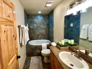 La salle de bains est pourvue d'un lavabo, de toilettes et d'une baignoire. dans l'établissement Backwoods Bonanza - Big Cabin With Hot Tub!, à Duck Creek Village