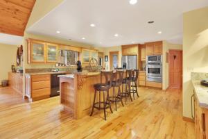 eine Küche mit Holzschränken und eine Bar mit Hockern in der Unterkunft Fawnskin Log Cabin- Luxurious Group Log Cabin Estate- Hot Tub- Walk to Lake in Fawnskin + 33 Fotos