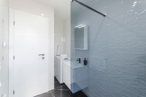 een witte badkamer met een wastafel en een douche bij Apartments Ella in Vodice