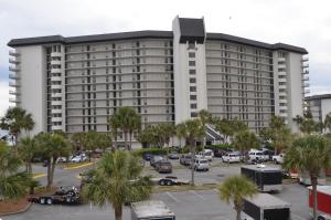 a large white building with palm trees in a parking lot at Gulf front condo in Panama City Beach
