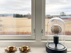um cloche de vidro sentado no peitoril de uma janela ao lado de duas placas de ouro em Holiday home VÄSTRA ÄMTERVIK em Östra Ämtervik