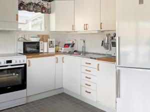 La cuisine est équipée de placards blancs et d'un réfrigérateur blanc. dans l'établissement Holiday home LJUNGSKILE VI, à Ljungskile