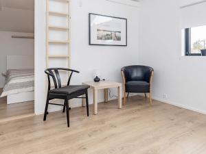 ÅlbækにあるHoliday home Ålbæk XXXIVの椅子2脚、テーブル1台、棚1台が備わる客室です。