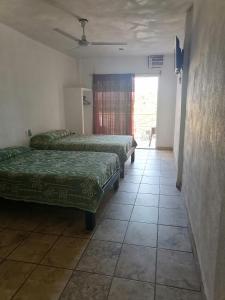 a row of beds in a room with a window at Posada El Balcon in Rincon de Guayabitos