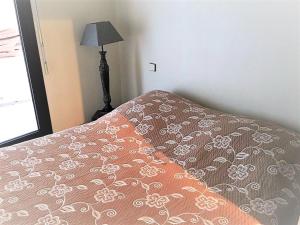 a bed with a blanket and a lamp in a room at Appartement Ciboure, 2 pièces, 4 personnes - FR-1-4-673 in Ciboure
